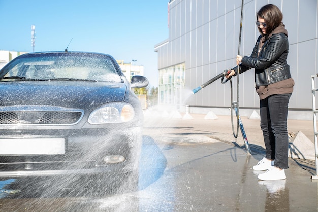 mujer joven, lavado, coche, en, autoservicio, carwash