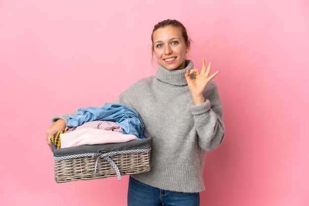 Mujer joven lavando ropa aislado en rosa