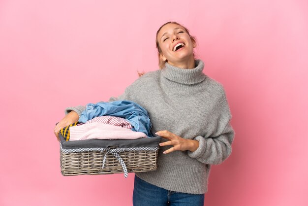 Mujer joven lavando ropa aislado en rosa