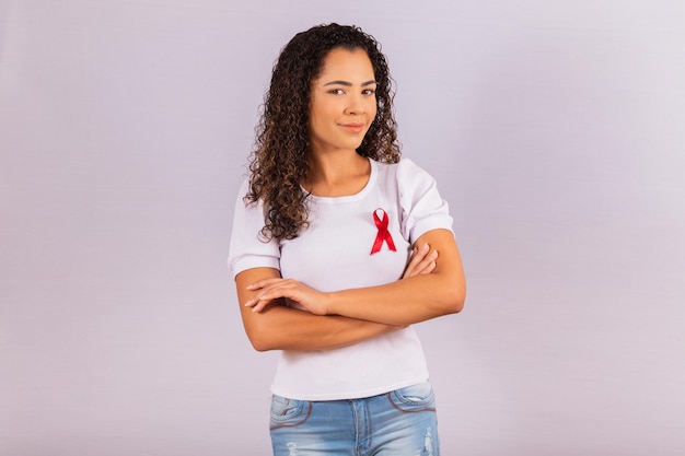 Mujer joven con lazo rojo en la camiseta para la campaña de prevención del VIH. Brazos cruzados