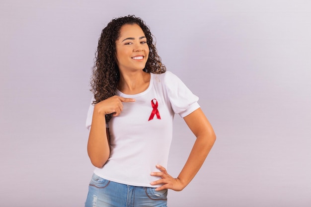 Mujer joven con lazo rojo en la camiseta para la campaña de prevención del VIH. Señalando