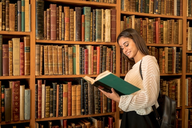 Mujer joven, lectura, cerca, estante