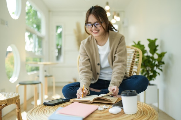 Foto una mujer joven lee un libro y se sienta cómodamente en una silla en casa