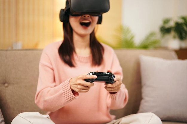 Mujer joven lesbiana con suéter y gafas de realidad virtual mientras sostiene el joystick para jugar videojuegos