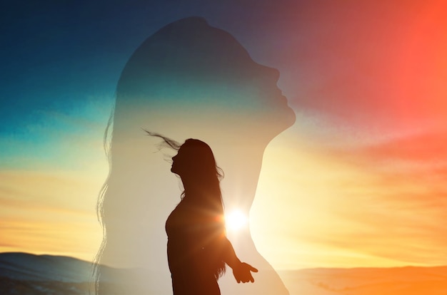 Foto mujer joven con levantar las manos sobre el fondo del cielo al atardecer.