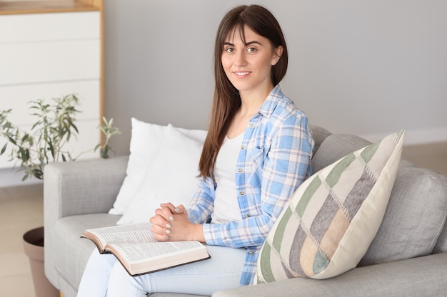 Mujer joven leyendo la Biblia en casa