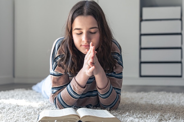 Foto una mujer joven está leyendo la biblia mientras está acostada en el suelo