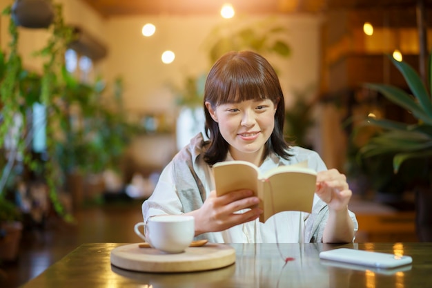 Una mujer joven leyendo un libro en un ambiente cálido.