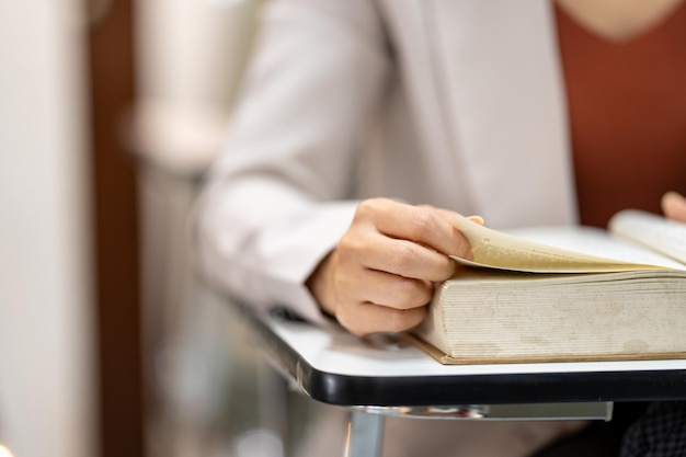 Mujer joven leyendo un libro en la biblioteca de la universidad