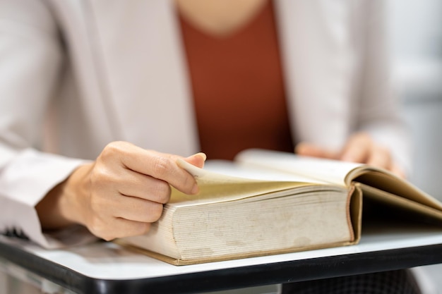 Mujer joven leyendo un libro en la biblioteca de la universidad