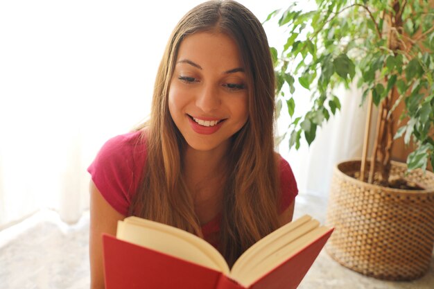 Foto mujer joven leyendo un libro en casa