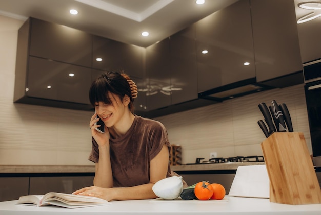 Mujer joven leyendo un libro de cocina en la cocina buscando una receta