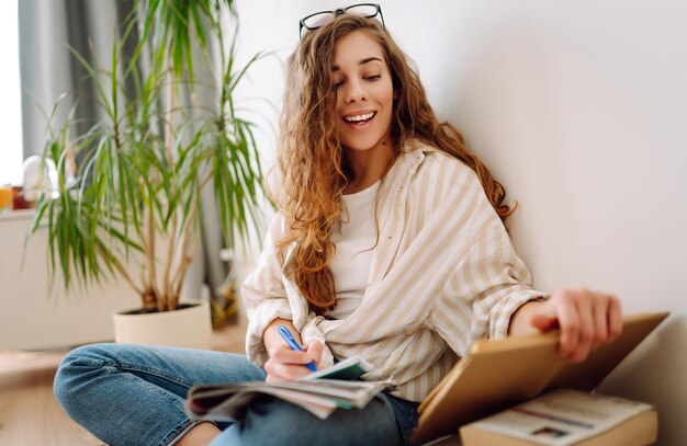 Mujer joven leyendo un libro escribiendo notas haciendo tareas en casa Concepto de descanso relajación