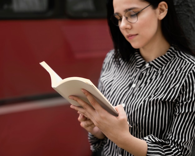 Foto mujer joven leyendo un libro interesante al aire libre