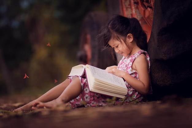 Mujer joven leyendo un libro mientras está sentada en el campo