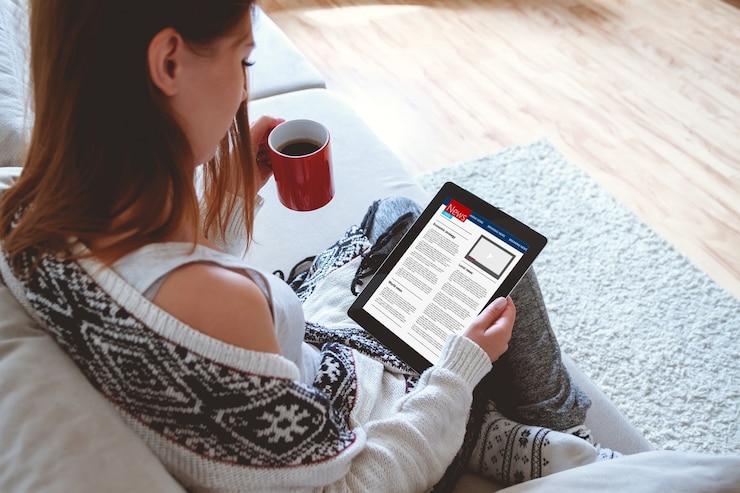 Foto mujer joven leyendo noticias con tableta mientras está sentado en el sofá en casa