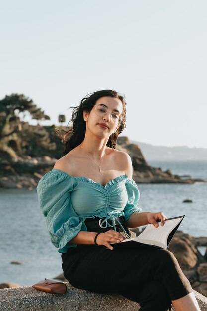 Mujer joven leyendo en la playa durante una super puesta de sol