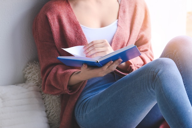 Mujer joven, libro de lectura, en casa, primer plano