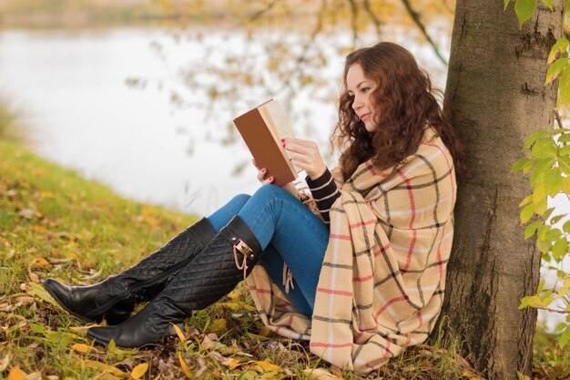 Mujer joven con libro en el parque en otoño