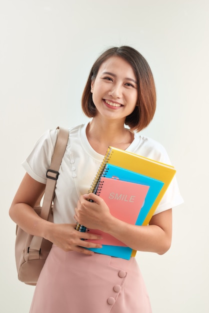 Mujer joven con libros y mochila sobre fondo blanco
