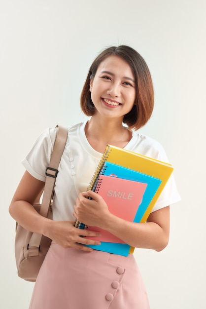 Mujer joven con libros y mochila sobre fondo blanco.