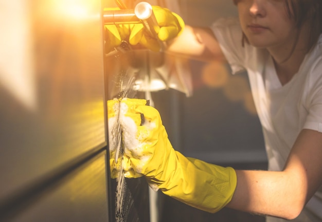 Foto mujer joven limpiando el horno de la cocina con un trapo en casa, fondo del concepto de servicio de tareas domésticas