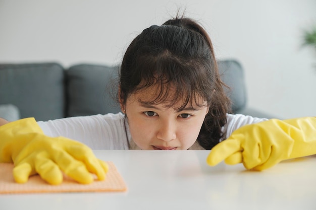 Mujer joven limpiando la mesa con guantes en casa