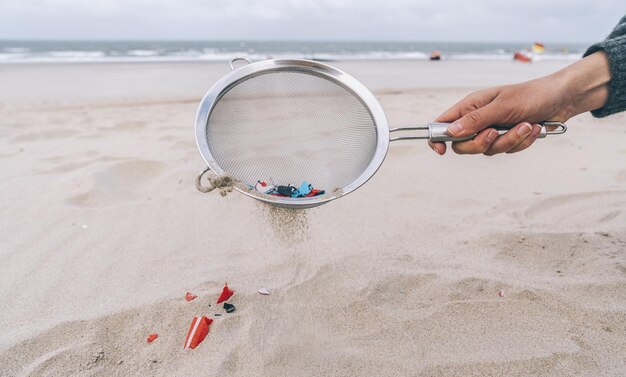 Foto mujer joven limpiando microplásticos de arena en la playa, problema ambiental, contaminación, ecosistema y concepto de advertencia de cambio climático