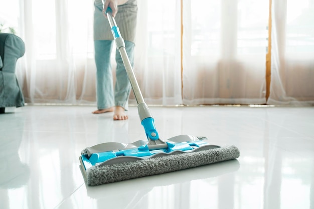 Mujer joven limpiando el piso usando un trapeador en casa