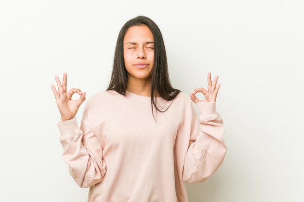 La mujer joven linda del adolescente hispánico se relaja después del día de trabajo duro, ella está realizando yoga.