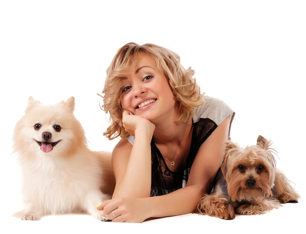 Mujer joven linda que abraza a sus perros mientras que se sienta aislado en blanco - retrato