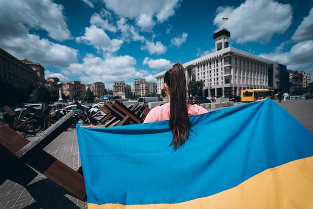 Mujer joven lleva la bandera de Ucrania ondeando detrás de ella