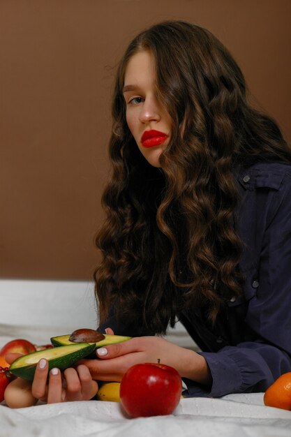 Mujer joven, llevando, lápiz labial rojo, posar, con, frutas