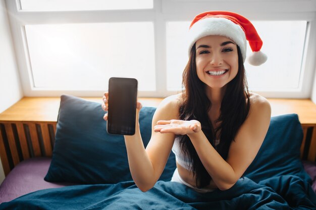 Mujer joven, llevando, santa, utilizar, smartphone