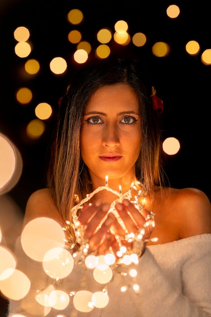 Foto mujer joven con luces de navidad