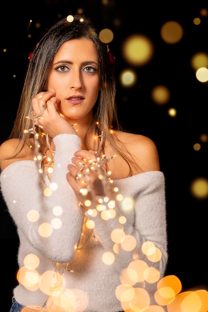 Foto mujer joven con luces de navidad
