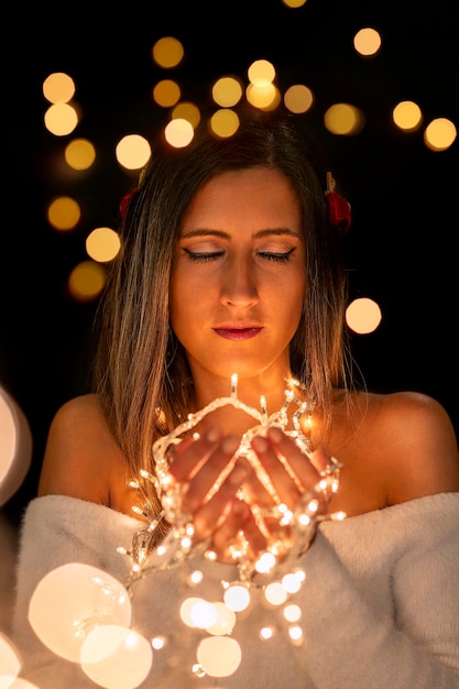 Foto mujer joven con luces de navidad