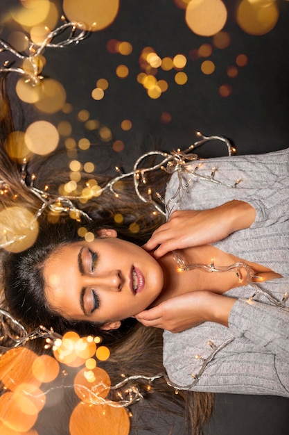 Foto mujer joven con luces de navidad