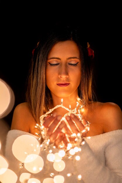 Foto mujer joven con luces de navidad