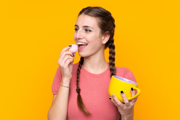 Mujer joven con macarons sobre pared aislada