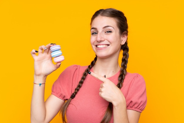 Mujer joven con macarons sobre pared aislada