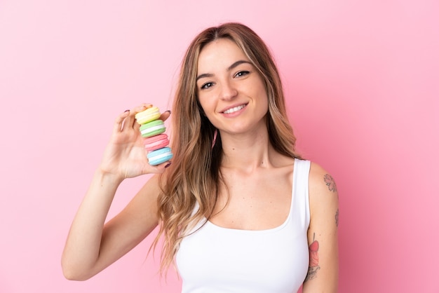 Mujer joven con macarons sobre pared rosa aislado sonriendo mucho