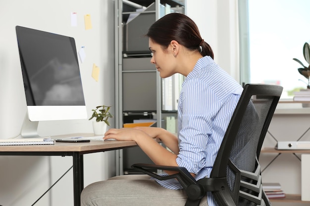 Mujer joven con mala postura sentada en el lugar de trabajo en la oficina Síntoma de escoliosis