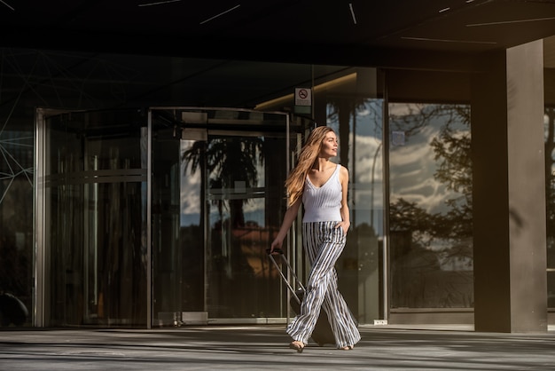 Mujer joven con maleta caminando por la calle