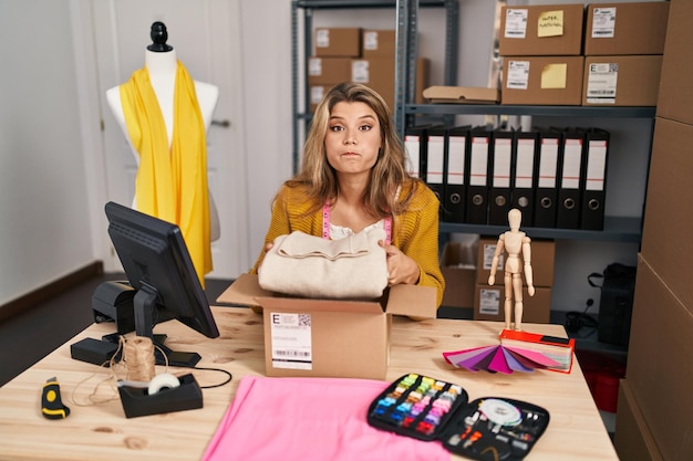 Mujer joven por maniquí en el pedido de embalaje de pequeñas empresas inflando las mejillas con cara divertida. boca inflada con aire, atrapando aire.