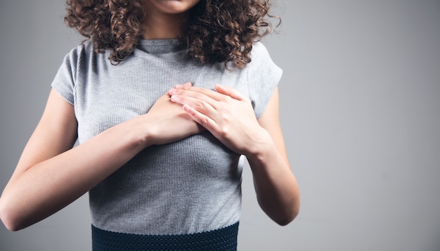 Mujer joven con la mano en el corazón del dolor.