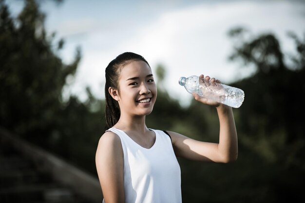 Mujer joven con la mano sujetando una botella de agua después de hacer ejercicio