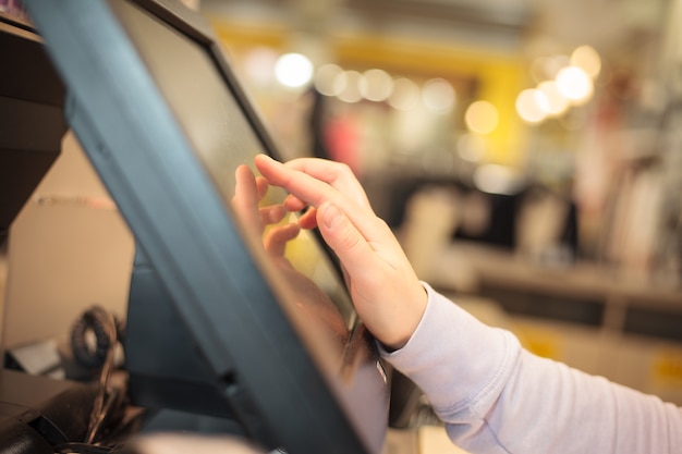 Mujer joven con la mano en el tacto de la tesorería cobrando el precio de una factura