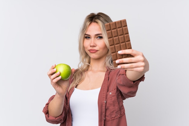 Mujer joven con manzana un chocolate sobre fondo aislado