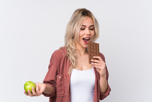 Mujer joven con manzana un chocolate sobre fondo aislado